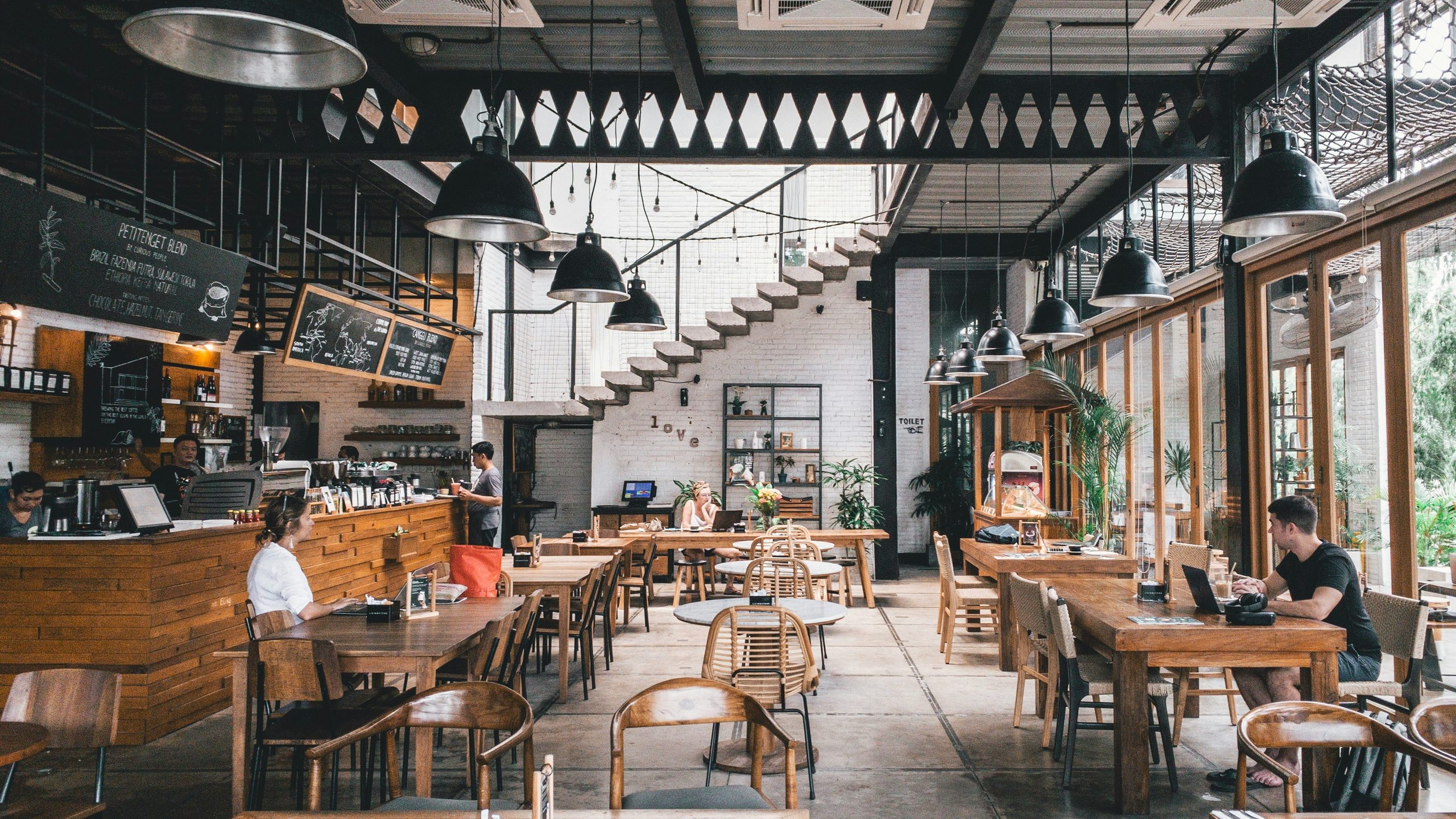 Industrial dining room with black pendant lamps and rattan-back chairs